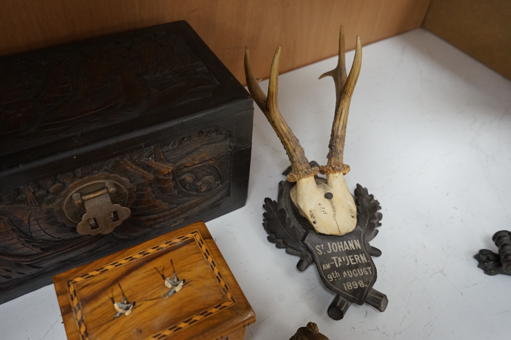 A Chinese carved wood box, two pairs of mounted deer horns, two carved wood cherub heads, an ashtray and an olivewood box, large box 29.5cm x 15cm high. (7)
